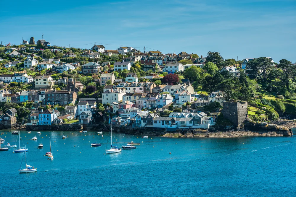 Estuary village of slate-roofed houses above a deep blue channel with yachts at anchor